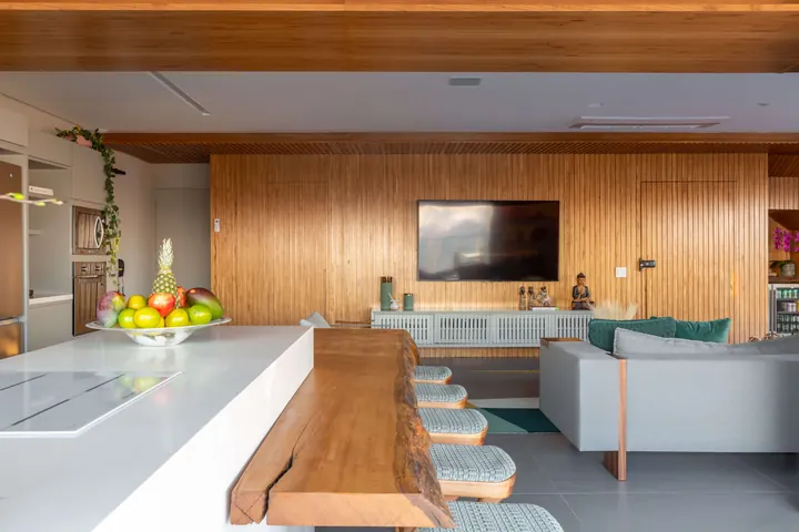 Cozinha integrada ao living com bancada em madeira maciça e painel ripado na Cobertura Imperatriz Leopoldina
